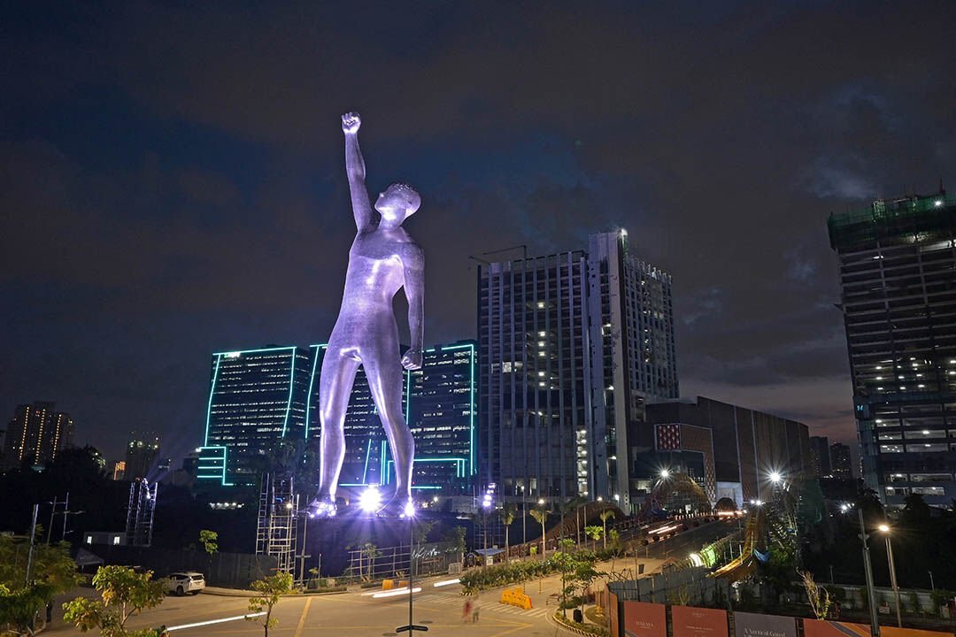 Illuminated giant statue and lit towers at Bridgetowne Destination Estate in Pasig at night